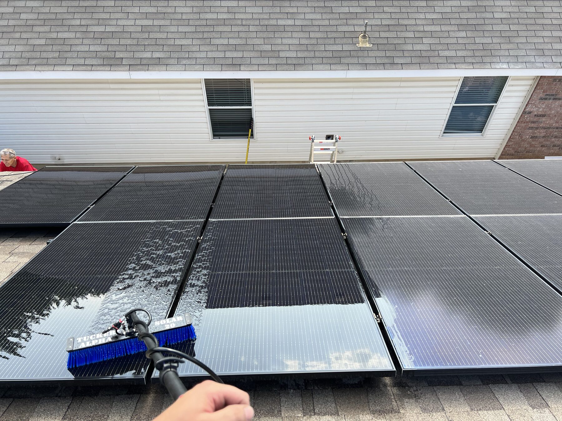 Water-fed brush cleaning a residential solar array